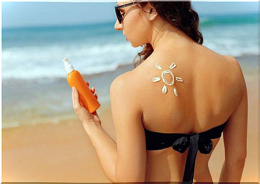 A woman at the beach with sunscreen on her back