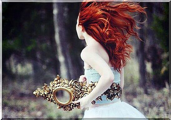 Redhead woman with mirror in hand